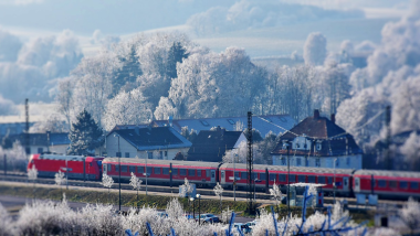 Ein Zug fährt durch das verschneite Bayern.